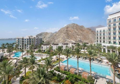 a view of a resort with palm trees and a pool at Bespoke Holiday Homes - Seaside Luxury 2BR in Address Residence, Fujairah in Fujairah