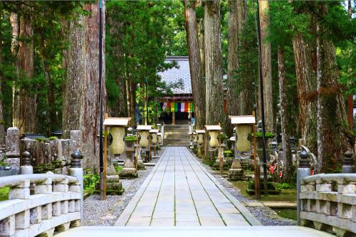 a path through a forest of trees with a bridge at Sanso Amanosato in Katsuragi