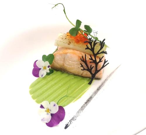 a piece of fish on a plate with flowers at Hotel Antines in La Villa