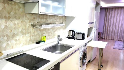 a kitchen with a sink and a washing machine at Geoje Residence Hotel in Geoje
