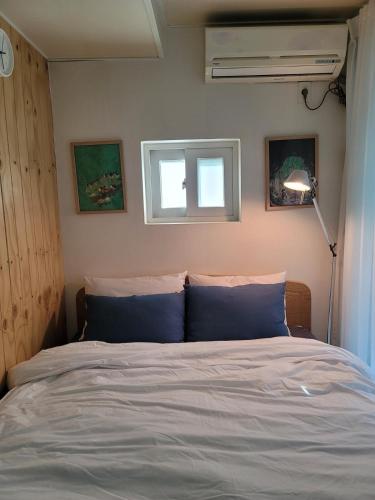 a bedroom with a bed with blue pillows and a window at K-WON Stay in Seoul