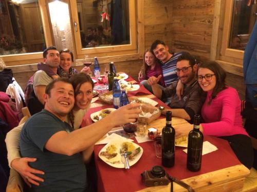 a group of people sitting around a table eating food at Rifugio Luna Nascente in San Martino