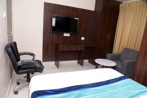 a room with a bed and a chair and a tv at Hotel KGB Coolriver in Visakhapatnam