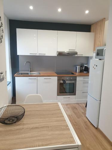 une cuisine avec des armoires blanches et un réfrigérateur blanc dans l'établissement Appartement agréable en plein cœur de ville, à Raon-lʼÉtape