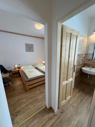 a bedroom with a bed and a bathroom with a sink at Penzion Star Doksy in Doksy