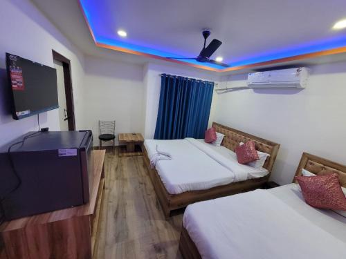 a room with two beds and a flat screen tv at Pavilion City Hotel in Nowgong