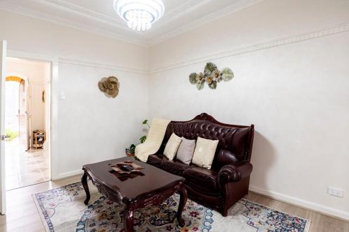 a living room with a leather couch and a table at Cozy Heritage Home 10mins walk to Wollongong Hospital with Free Parking and Fast Internet in Wollongong