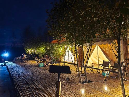 a group of people sitting at tables in a park at night at หลานย่าโฮมสเตย์ บางตะบูน in Ban Khung Tamnak