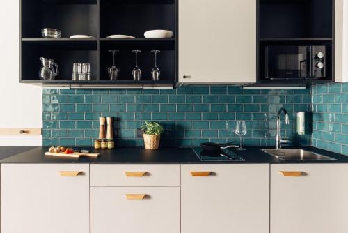 a kitchen with white cabinets and a blue tile wall at harry's home Graz-Smart City hotel & apartments in Graz