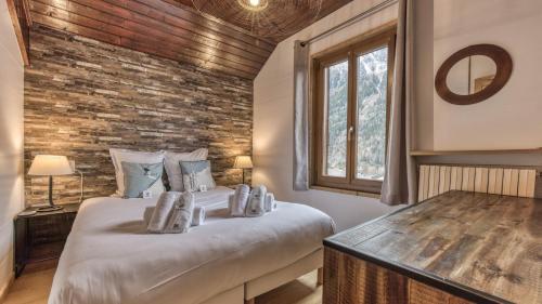 une chambre avec un lit et un mur de briques dans l'établissement Chalet Para, à Chamonix-Mont-Blanc