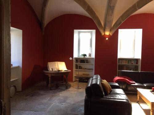 - un salon avec des murs rouges et un canapé dans l'établissement La Maison du Voyageur 1546, à Passavant