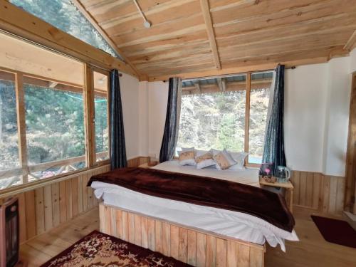 a bedroom with a bed in a room with windows at Shreya cozy hut in Sainj