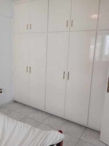 a room with white cabinets and a bed in it at Eat well Sleep Well in Larnaca