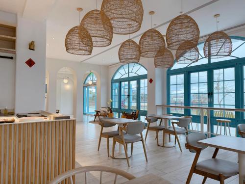 Un restaurante con mesas, sillas y ventanas. en Little Greece, en Nanwan