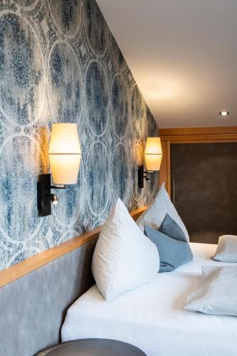two beds in a hotel room with two lamps at Hotel Königgut in Wals