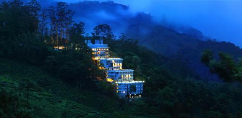 a building on the side of a mountain at night at Chandys Windy Woods Munnar in Munnar