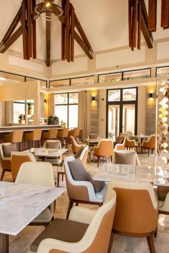 a restaurant with tables and chairs and windows at Golf du Rova Luxury Hotel in Antananarivo