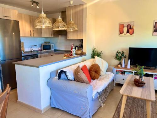 a living room with a couch and a kitchen at Condado de Alhama, JARDIN 13 SV64 in El Romero