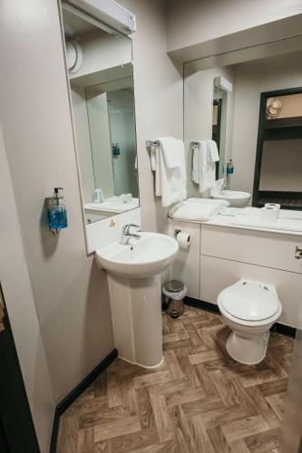 a bathroom with a sink and a toilet and a mirror at Cat & Lion Country Pub and Hotel in Warrington