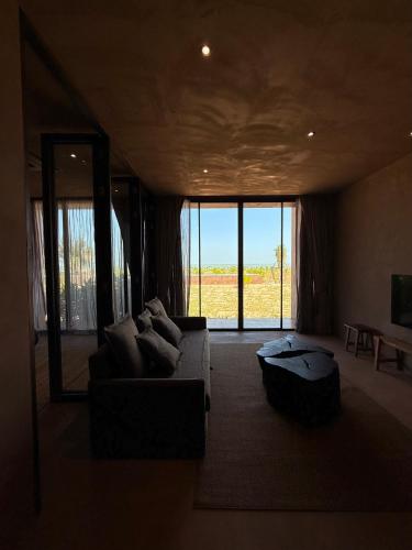 a living room with a couch and a large window at inchantreedoolay huahin in Pran Buri