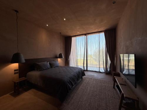 a bedroom with a bed and a large window at inchantreedoolay huahin in Pran Buri