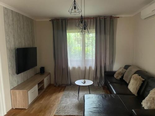 a living room with a couch and a tv at Alice Vendégház in Kalocsa