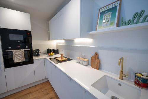 a kitchen with white cabinets and a sink at Sunshine in Eastbourne