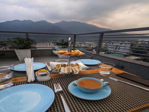 a table with plates of food on a balcony at LA Riqueza Pride Inn # Rootop Swimming Pool with Mountain View # Free Parking # Tapovan # Center of Rishikesh# in Rishīkesh