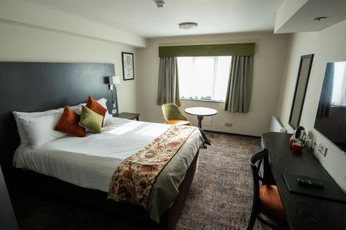 a hotel room with a large bed and a desk at Cat & Lion Country Pub and Hotel in Warrington