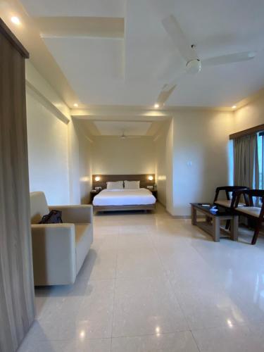 a bedroom with a bed and a couch and a table at The Byke Skylark Seafront Resort, Dapoli in Murūd