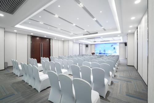 a conference room with white chairs and a screen at Victoria Hotel Guangzhou Zhujiang New Town - Free shuttle bus during Canton Fair period in Guangzhou