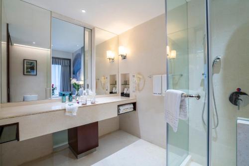 a bathroom with a shower and a sink and a mirror at Victoria Hotel Guangzhou Zhujiang New Town - Free shuttle bus during Canton Fair period in Guangzhou