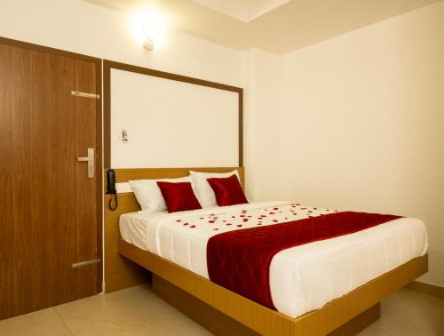 a bedroom with a large bed with red pillows at Hotel Eden Palace in Trichūr