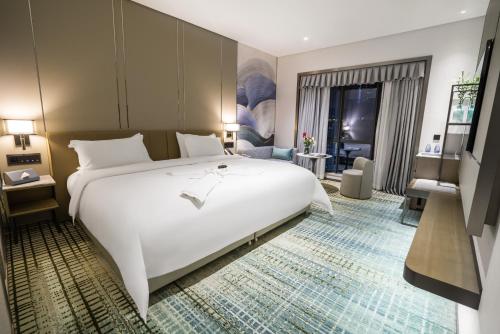 a bedroom with a large white bed and a living room at Victoria Hotel Guangzhou Zhujiang New Town - Free shuttle bus during Canton Fair period in Guangzhou