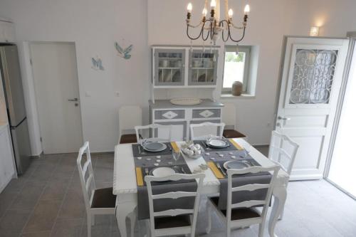 a dining room with a white table and chairs at Logaras' Villas in Logaras