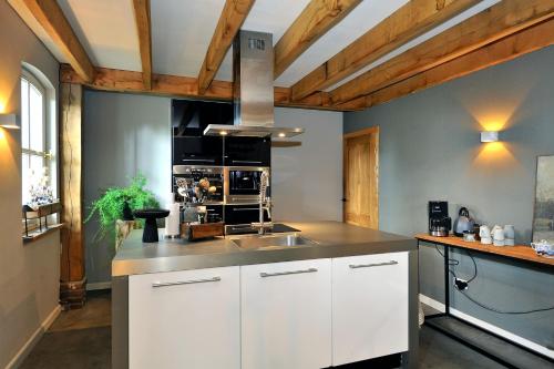 a kitchen with white cabinets and a stainless steel sink at Antoniushofke in Asten