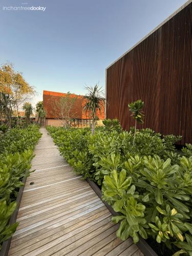 a wooden walkway in a garden with green plants at inchantreedoolay huahin in Pran Buri