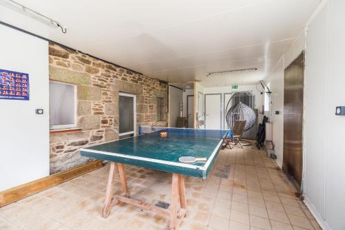 a ping pong table in a room with a brick wall at Ancien Moulin rénové à neuf pour 20 personnes sur les rives du Trieux in Plésidy