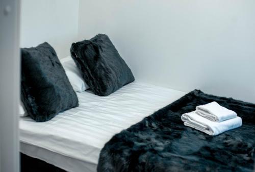 a bed with two black pillows and towels on it at Northern Star Apartment 4 in Ivalo