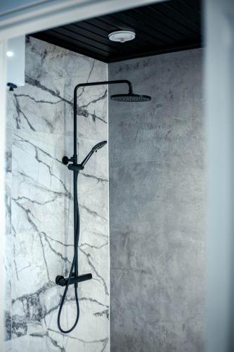 a shower in a bathroom with a marble wall at Northern Star Apartment 4 in Ivalo