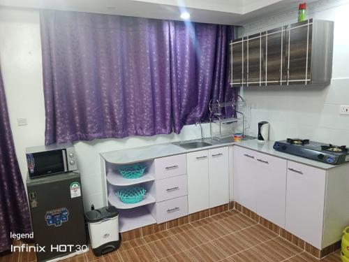 ナニュキにあるJukins one bedroom homeの白いキャビネットと紫色のカーテンが備わるキッチン