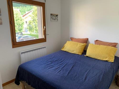 une chambre avec un lit avec des draps bleus et une fenêtre dans l'établissement Appart proche plage, piscine et base nautique, à Malbuisson