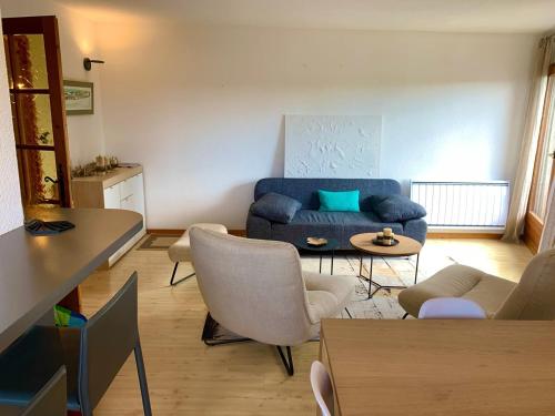 un salon avec un canapé bleu et des chaises dans l'établissement Appart proche plage, piscine et base nautique, à Malbuisson