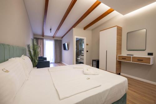 a bedroom with a white bed and a tv at Golemi Lux Hotel in Golem