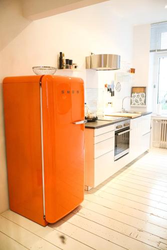 an orange refrigerator in a kitchen with white cabinets at Apartments "Am Rheinorange", Netflix & Prime in Duisburg