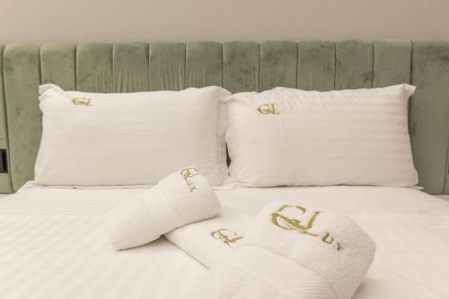 a white bed with two white pillows with gold initials at Golemi Lux Hotel in Golem