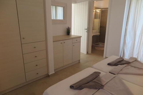 a white bedroom with two beds and a dresser at Logaras' Villas in Logaras