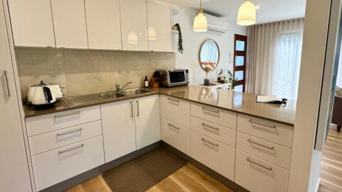 a kitchen with white cabinets and a sink at Noosa Bliss - Self Contained, Shared Pool, Tennis, Gym in Noosa Heads
