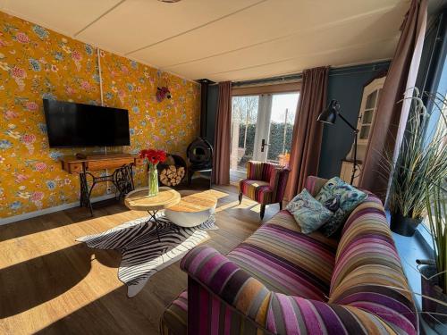 a living room with a couch and a tv at Eekhoorn, vakantiehuis met barrelsauna in Voorthuizen