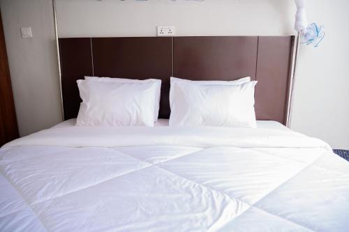 a large white bed with white sheets and pillows at Stadium View Executive Guest House in Lilongwe